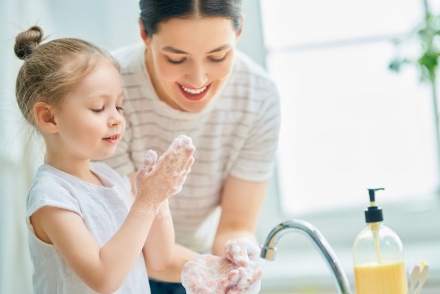 girl and her mother are washing hands